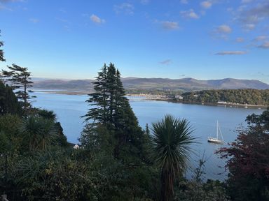 A view of water with trees and mountains at Afallon in Menai Bridge