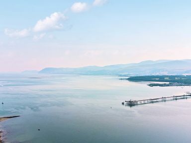 An aerial view of a pier over calm water with mountains in the background at Afallon in Menai Bridge