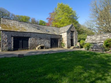 A building with a stone exterior and wooden features at Carrows Stable in Morwenstow