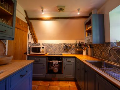 A kitchen with a microwave and oven at Carrows Stable in Morwenstow