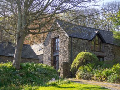 A stone house with windows and grass in front at Carrows Stable in Morwenstow