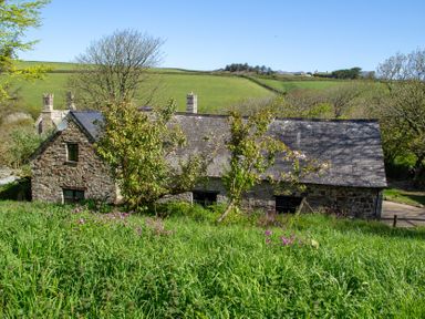 A house with trees and flowers in front at Carrows Stable Morwenstow
