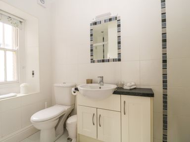 A bathroom with a toilet sink mirror and window at Glen Cottage in Troutbeck near Keswick
