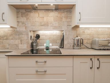 A kitchen counter with a stovetop kettle toaster and utensils at Oak Cottage in Windermere