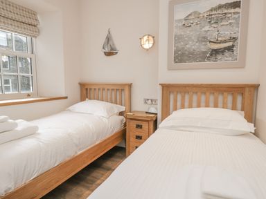 A bedroom with two single beds and a wooden nightstand between them at Oak Cottage in Windermere