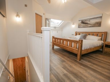 A bedroom with wooden bed and side table a painting above the bed and a skylight window at Oak Cottage in Windermere