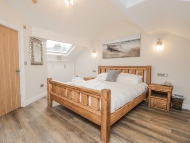 A bedroom with a wooden bed white bedding and bedside tables under a skylight at Oak Cottage in Windermere