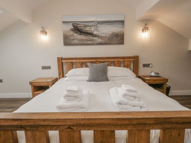 A bedroom with a wooden bed frame white bedding and towels on the bed at Oak Cottage in Windermere
