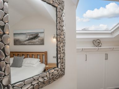 A bedroom reflected in a decorative mirror with a wooden bed frame a nightstand and a painting of a boat at Oak Cottage in Windermere