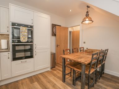 A kitchen with built-in ovens a wooden dining table and chairs at Oak Cottage in Windermere
