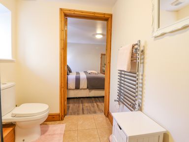 A bathroom with a toilet towel rail and a white cabinet looking into a bedroom at Gwennol Cottage in Golden Grove near Llandeilo