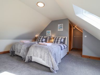 A bedroom with two single beds side by side under a sloped ceiling at Gwennol Cottage in Golden Grove near Llandeilo