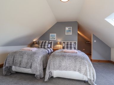 A bedroom with two single beds lamps and framed pictures on a wall at Gwennol Cottage in Golden Grove near Llandeilo