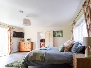 A bedroom with a bed and wooden furniture and a television on the wall at Sewin Cottage in Golden Grove near Llandeilo