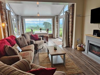 A living room with sofas and a coffee table near a dining area with a table and chairs at Sewin Cottage Golden Grove near Llandeilo