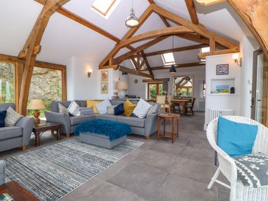 A living room with gray sofas and wooden beams on the ceiling at Balog Farm in Amlwch