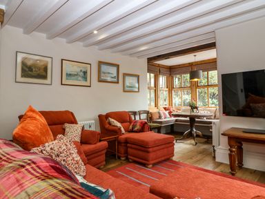 A living room with orange seating and framed pictures on the wall at Balog Farm in Amlwch