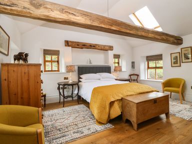 A bedroom with a wooden chest at the foot of the bed and wooden beams on the ceiling at Balog Farm in Amlwch