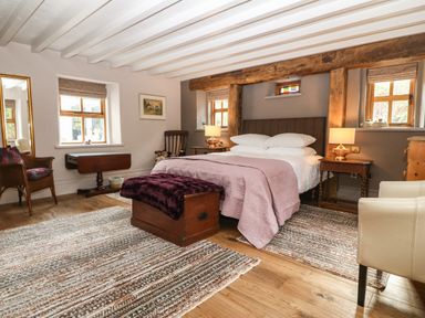 A bedroom with a double bed bedside tables wooden chest and various chairs at Balog Farm in Amlwch