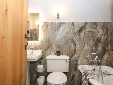 A bathroom with a toilet sink bathtub and wooden door at Balog Farm in Amlwch