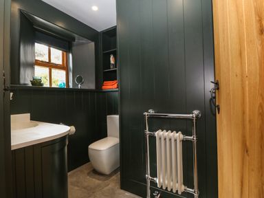 A bathroom with a toilet sink window and radiator at Balog Farm in Amlwch