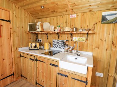 A wooden kitchen with a sink toaster kettle microwave plates and utensils at Elan in Rhayader