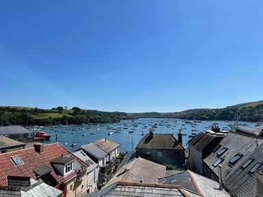 A view of rooftops overlooking boats on a river with hills in the background at The Penthouse in Salcombe