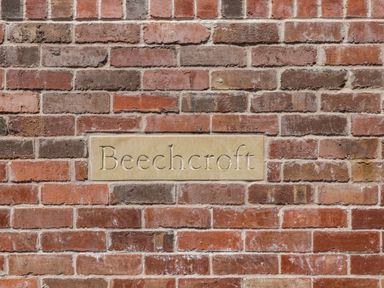 A brick wall with a rectangular stone plaque engraved with the word Beechcroft