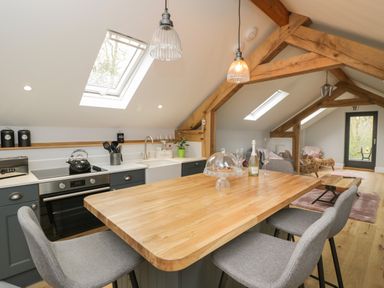 A kitchen with wooden countertop island and grey chairs under skylights at Lugg View in Cross Keys near Hereford