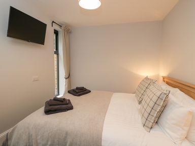 A bedroom with a bed a wall-mounted television and a window with curtains at Lugg View in Cross Keys near Hereford