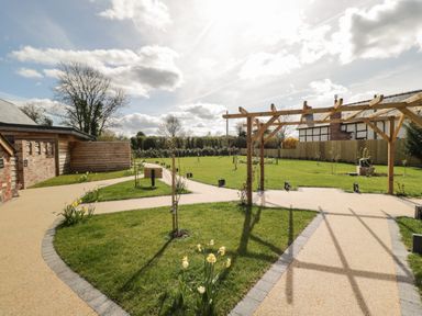A garden with pathways wooden pergola and green lawn at Lugg View in Cross Keys near Hereford