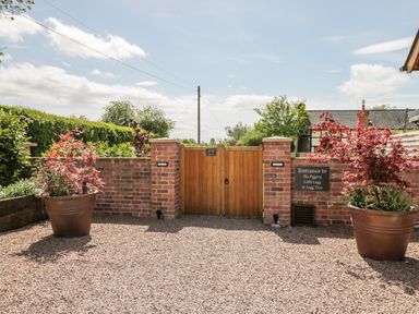An entrance gate with brick walls and large potted plants on either side at Lugg View in Cross Keys near Hereford