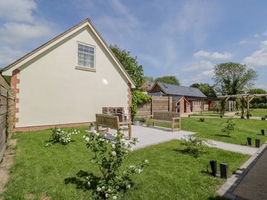 An outdoor garden area with benches and a fireplace near a house at Lugg View in Cross Keys near Hereford
