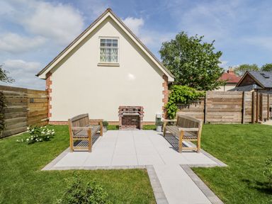 A paved area with two wooden benches and a small brick fireplace in a garden at Lugg View in Cross Keys near Hereford