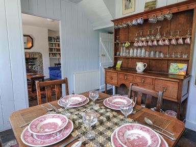A dining room with a table set for dinner at Dolwylan Cottage in Cwmtydu near New Quay