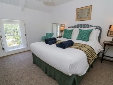 A bedroom with a bed and armchair at Dolwylan Cottage in Cwmtydu near New Quay