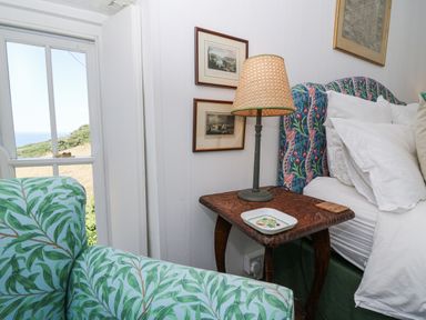 A bedroom with a bed, lamp, and chair at Dolwylan Cottage in Cwmtydu near New Quay