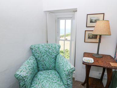 A snug with a green patterned chair and a table at Dolwylan Cottage in Cwmtydu near New Quay