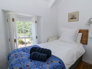 A bedroom with a bed and window at Dolwylan Cottage in Cwmtydu near New Quay