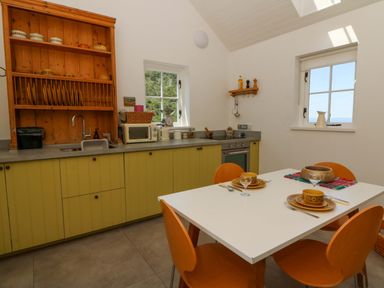 A kitchen with a table and chairs at Dolwylan Barn in Cwmtydu near New Quay