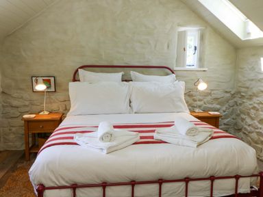 A bedroom with a bed and bedside tables at Dolwylan Barn in Cwmtydu near New Quay