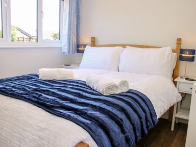 A bedroom with a bed covered with white bedding and a blue blanket with towels on the bed at Oakleigh in Four Crosses