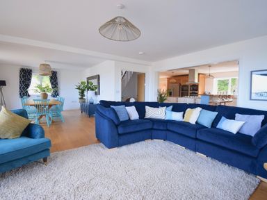 A living room with blue sofas and a dining area with blue chairs at Ty Ni in New Quay