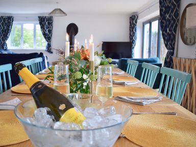 A dining table with candles flowers and a bottle of champagne in an ice bucket at Ty Ni in New Quay
