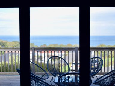 A balcony with round chairs and a table overlooking the sea at Ty Ni in New Quay