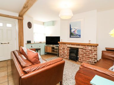 A living room with leather sofas a brick fireplace and a television at The Yellow House 13 King Street Dawlish