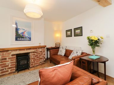 A sitting room with a brick fireplace brown leather sofas and a side table with flowers at The Yellow House 13 King Street in Dawlish