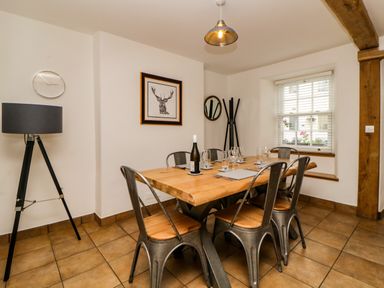 A dining room with a wooden table and metal chairs and a floor lamp by the wall at The Yellow House 13 King Street in Dawlish