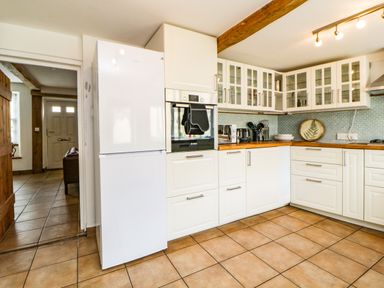 A kitchen with white cabinets a white refrigerator an oven and tiled floor at The Yellow House 13 King Street in Dawlish