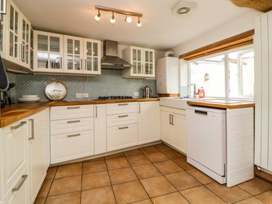 A kitchen with white cabinets wooden countertops a tiled floor and a window at The Yellow House 13 King Street in Dawlish